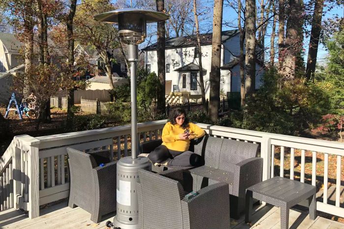 Person sitting on patio furniture next to an Amazon Basics Outdoor Propane Patio Heater with Wheels
