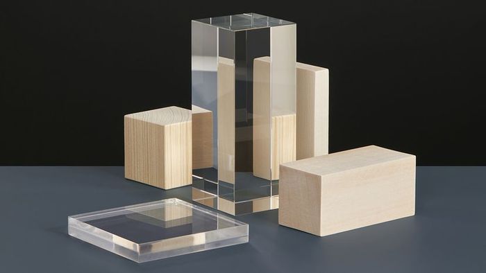 Glass and wooden prisms placed on a gray surface with a dark background