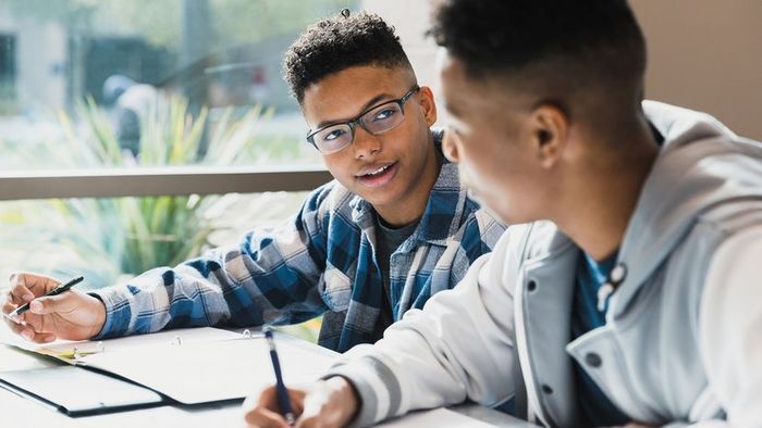 A teenager chats with their friend while they study together