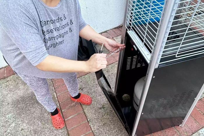A person adjusting the chain on the Thermo Tiki Outdoor Propane Patio Heater