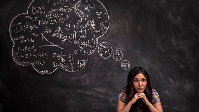 A woman seated in front of a blackboard, with a chalk thought bubble above her head