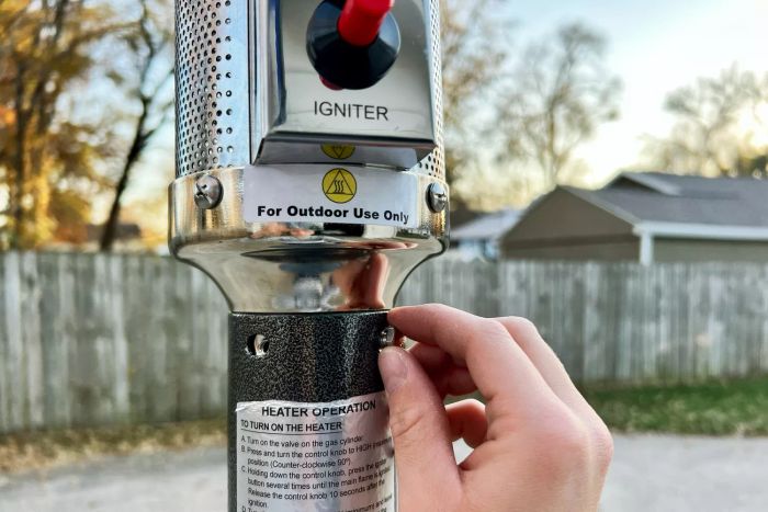 Closeup of a hand adjusting a screw on the AZ Patio Heaters Outdoor Patio Heater With Table.