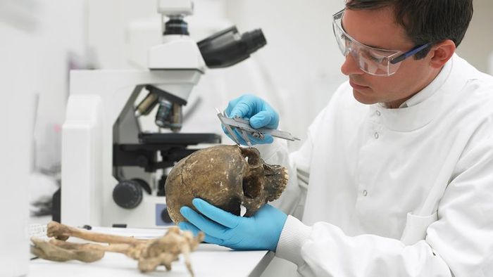 A scientist in a lab coat analyzing a decayed skull in a sterile laboratory environment
