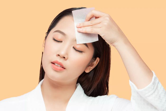 woman holding a facial blotting paper
