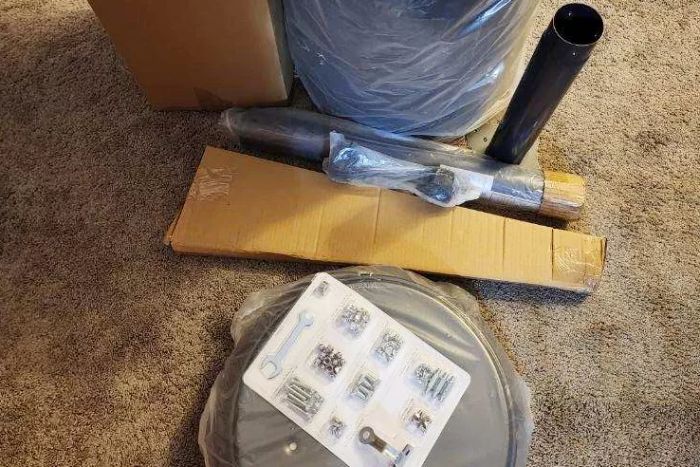 The parts for the East Oak Outdoor Patio Heater are neatly wrapped and displayed on a carpet.
