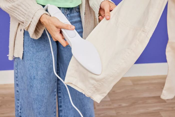 A detailed image of someone using the NORI Press Iron to smooth out off-white pants