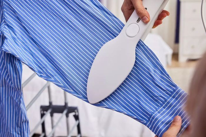 A detailed shot of someone using the NORI Press Iron to smooth out a dress shirt sleeve