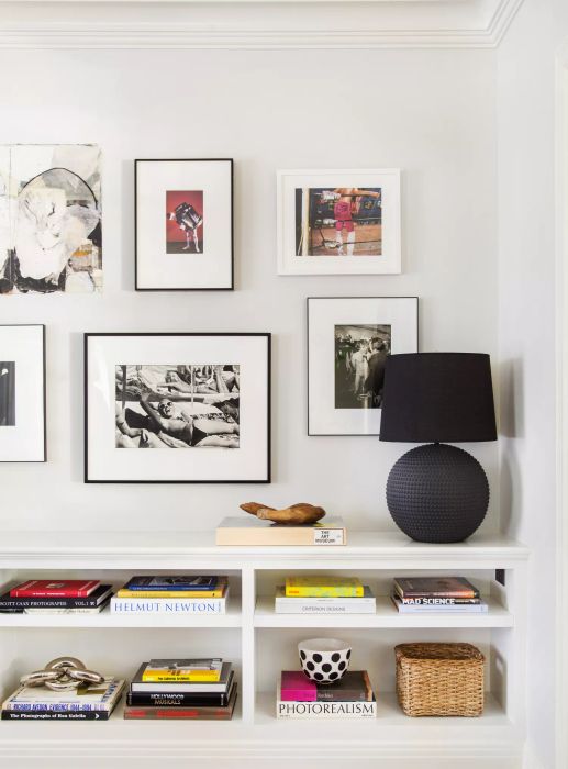 bookshelf beneath a gallery wall