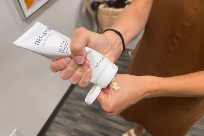 An individual applying Replenix Retinol Smooth + Tighten Body Lotion to their hand