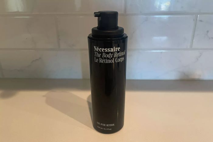 A bottle of Nécessaire The Body Retinol placed on a bathroom countertop