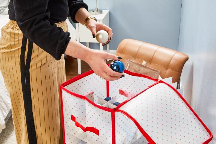 A person places ornaments inside the Sattiyrch Plastic Christmas Ornament Storage Box.