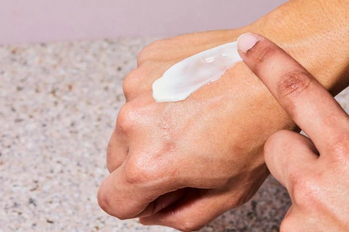 A finger applying Gold Bond Age Renew Retinol Overnight Body and Face Lotion to their hand