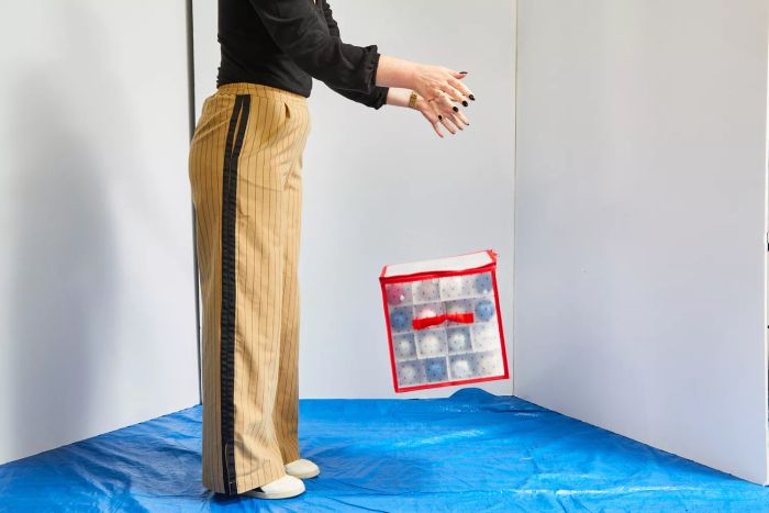 A person drops the Sattiyrch Plastic Christmas Ornament Storage Box.