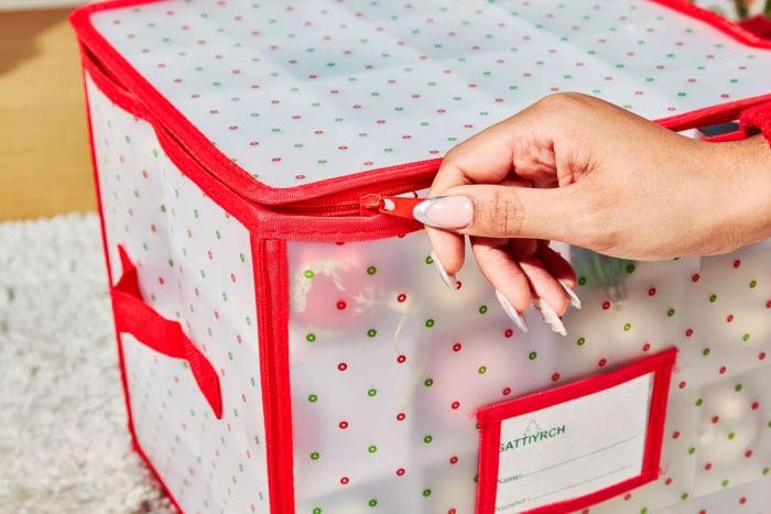 A person zips up the Sattiyrch Plastic Christmas Ornament Storage Box.