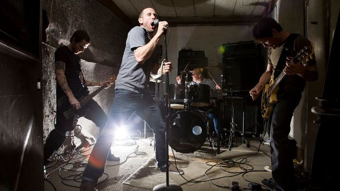 A rock band with four musicians rehearsing in a confined space.