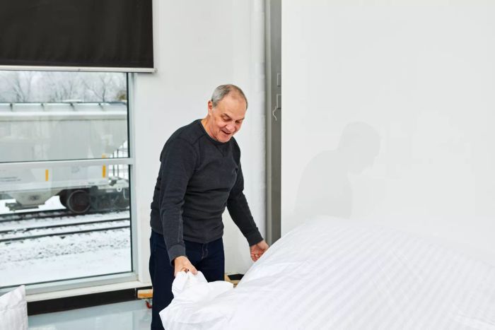 A person spreading out the Chateau Home Collection Egyptian Cotton Sheets on a bed