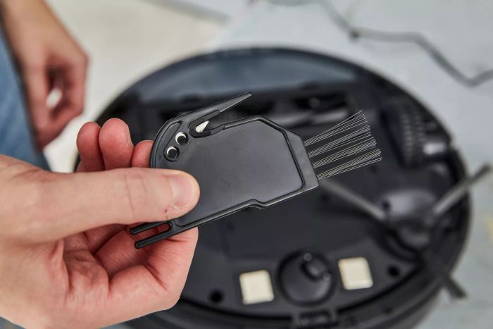 A hand holding the cleaning tool designed for the Black + Decker RoboSeries Robot Vacuum