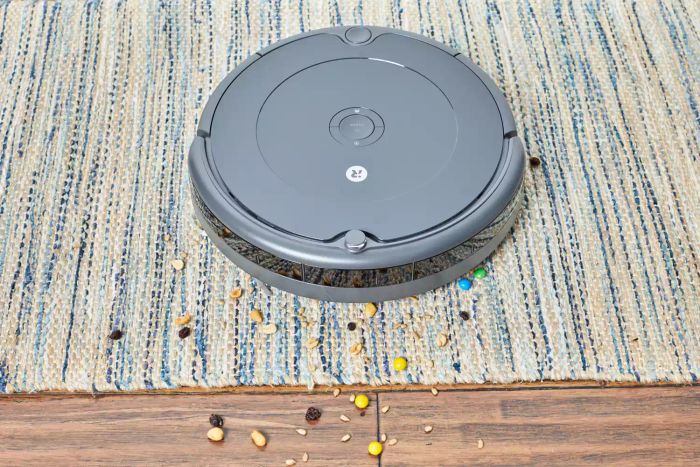 The iRobot Roomba 694 Robot Vacuum picking up trail mix from both a rug and a hardwood floor