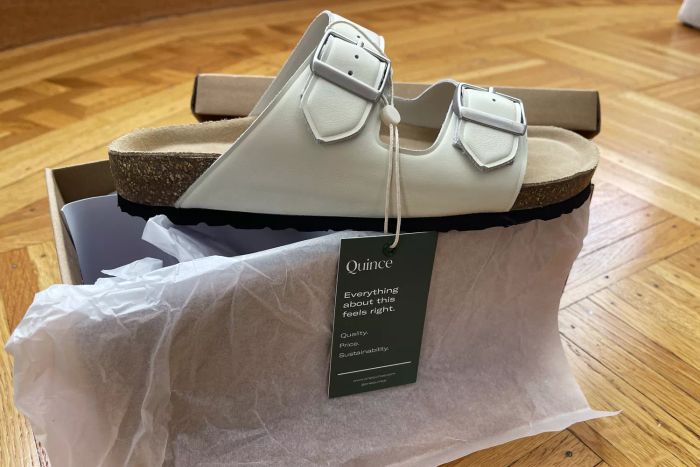 The Quince Nappa Leather Double Buckle Slides displayed on their shoebox.
