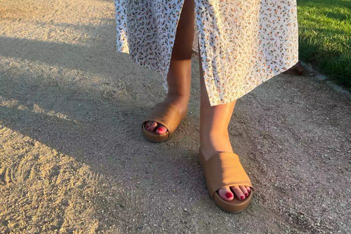 The Beek Pelican Leather Platform Sandal being worn by someone walking on gravel.