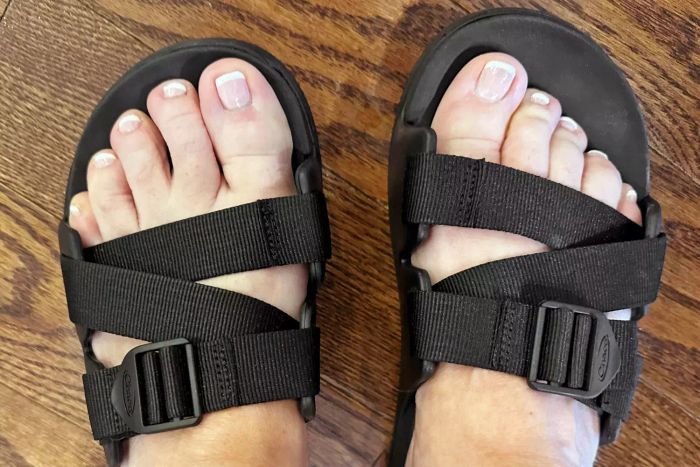 The Chaco Women’s Chillos Slide being worn by someone standing on a wooden floor.