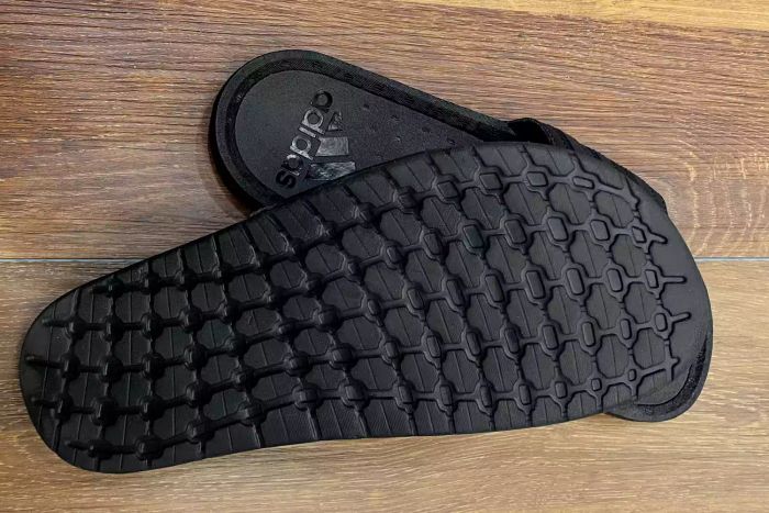 A detailed close-up of the tread on the bottom of the Adidas Adilette Boost Slides.