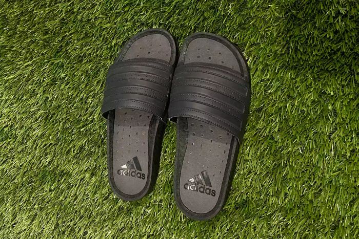 A top-down view of the Adidas Adilette Boost Slides on grass.