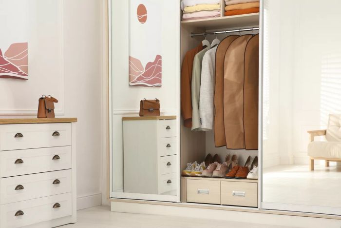 Clothes hanging in garment bags inside a wardrobe