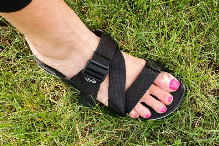 A close-up of the Chaco Women’s Lowdown Slide on a foot standing on grass.