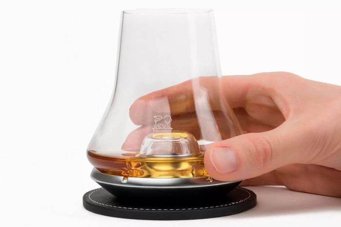 A person enjoying the Peugeot Whiskey Tasting Set, holding a glass filled with whiskey.