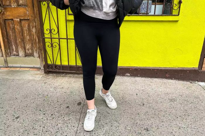 An individual adjusts the Spanx Booty Boost Active 7/8 Leggings outdoors