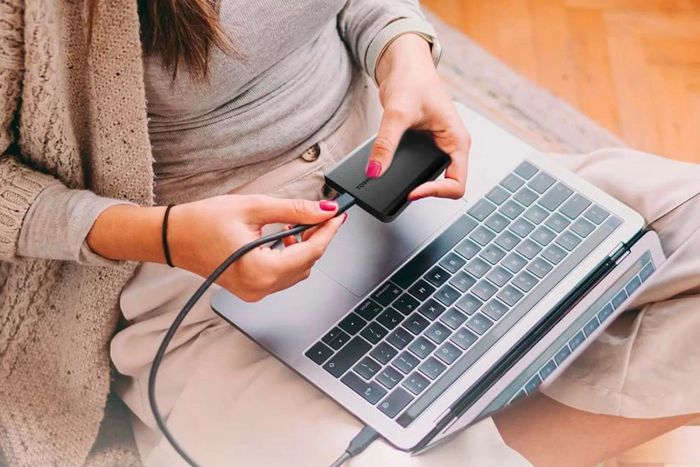 A person connecting the Toshiba Canvio Basics External Hard Drive to their laptop.