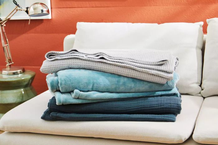 a pile of blankets on a white sofa