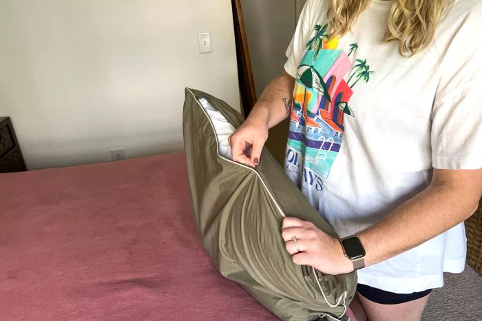 A person carefully zipping a pillow into the Brooklinen Classic Percale Pillowcases