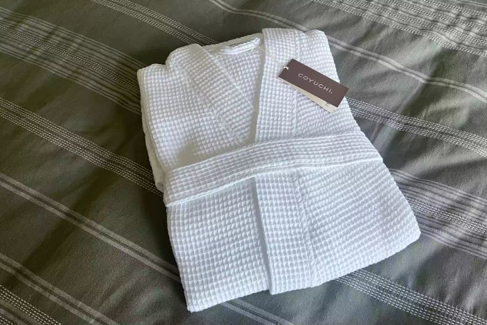 The Coyuchi Unisex Organic Waffle Robe neatly folded on a bed.