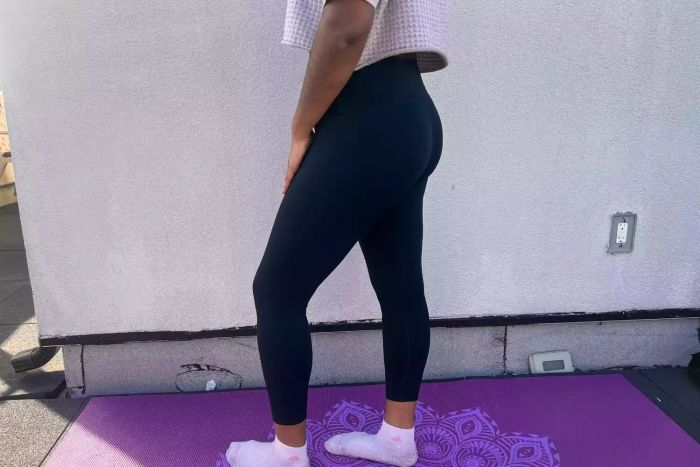 An individual stands on a yoga mat dressed in the Spanx Soft & Smooth Active 7/8 Leggings