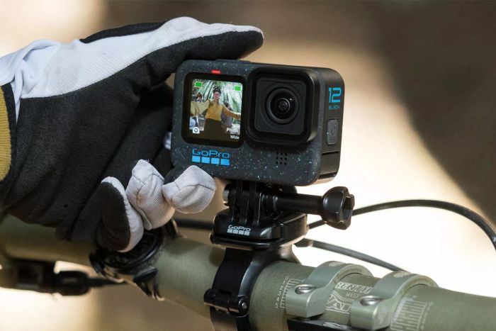 A person adjusts a GoPro HERO12 Black mounted on a bike handlebar.