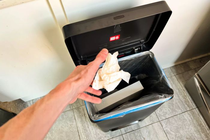 A person disposing of waste into the Rubbermaid 13 Gallon Premier Series II Trash Can