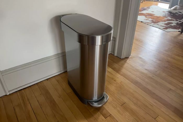The Simplehuman 12 Gallon Slim Hands-Free Kitchen Step Trash Can placed elegantly on a wooden floor