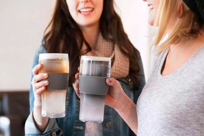 Two women holding Host Beer Freeze Pint Glasses.