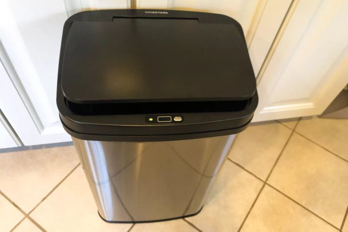 The NINESTARS DZT-50-28 13 Gallon Touchless Motion Sensor Trash Can placed on a tiled floor