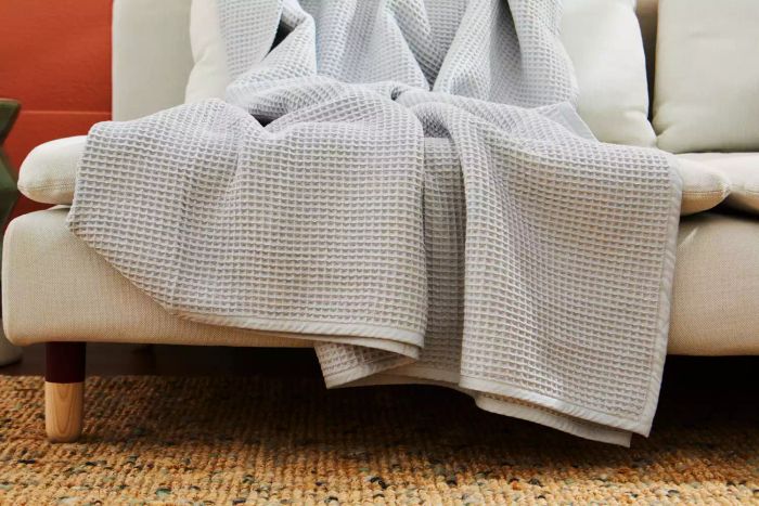 The Boll & Branch Waffle Bed Blanket elegantly placed over a couch
