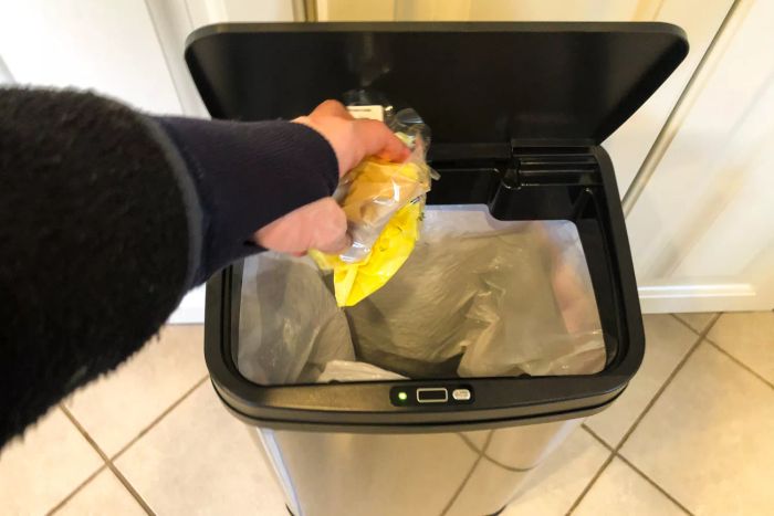 A person disposing of waste into the NINESTARS DZT-50-28 13 Gallon Touchless Motion Sensor Trash Can