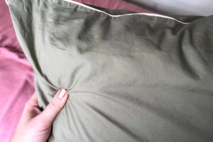 A person holding the Brooklinen Classic Percale Pillowcases with a pillow neatly inserted