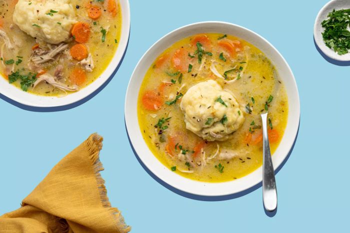 overhead view of two bowls of chicken and dumpling soup on a teal background