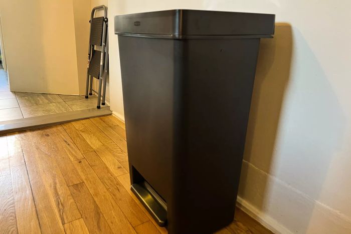 The Rubbermaid 13 Gallon Premier Series II Trash Can placed on a wooden floor