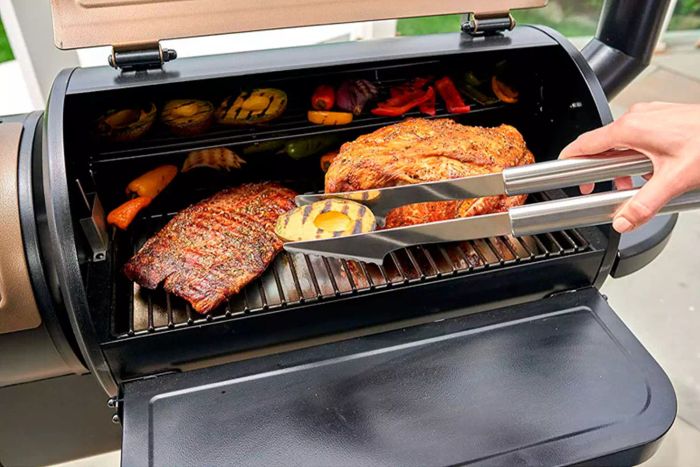 A tool from the Cuisinart 20-Piece Deluxe BBQ Grill Tool Set is being used to lift grilled avocado from the grill