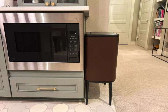 The Brabantia 3 + 6 Bo Touch Top Dual Compartment Recycling Trash Can positioned next to an oven