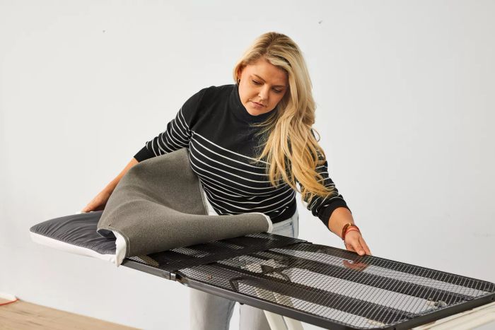 A person assembling the Reliable 320LB Home Ironing Board