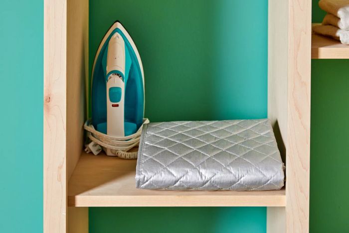 The BNYD Portable Ironing Mat Blanket neatly folded on a shelf alongside an iron